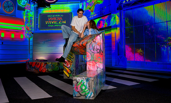 A couple posing in a neon street world at House of Hype